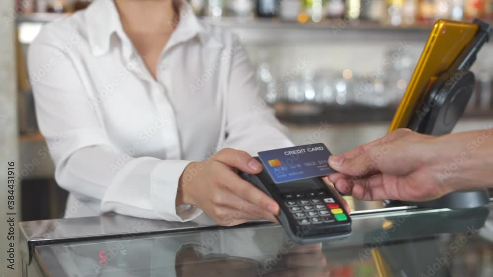 Close up man using credit card on wireless EDC with staff smiley face.
