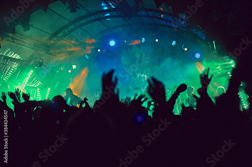 Abstract blur atmosphere: happy people enjoying outdoor music festival concert, raised up hands and clapping of pleasure, active night life concept, play of light and shadow on the stage © udmurd