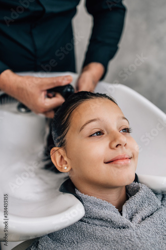 Young girl enjoying at hairstyle treatment while professional hairdresser gently washing her hair.
