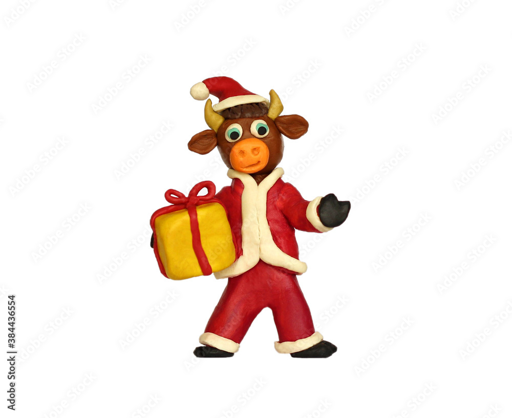 A small plasticine bull in a christmas red hat on a white background A small plasticine bull in a christmas red hat on a white background