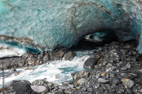 Scenic glacier ice caves with river flowing out from inside