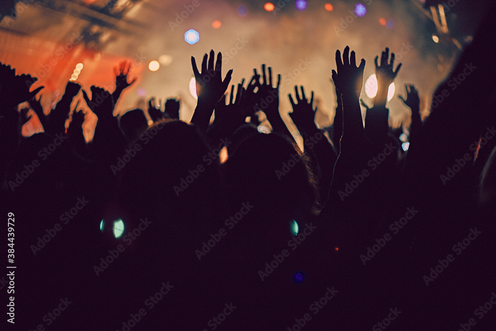 Abstract blur atmosphere: happy people enjoying outdoor music festival concert, raised up hands and clapping of pleasure, active night life concept, play of light and shadow on the stage
