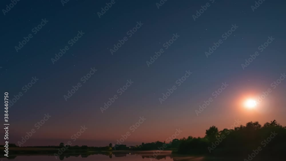 Timelapse of night sky above a calm lake with flat water surface