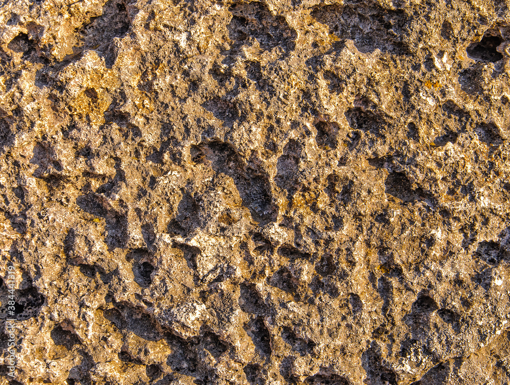 The dark gray stone is lit by the sun at sunset. Use for background.