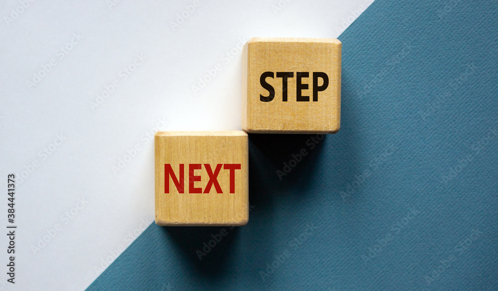 Conceptual image of motivation. Wooden cubes with words 'next step'. Beautiful white and blue background, copy space. Business concept. Conceptual image of motivation. Wooden cubes with words 'next step'. Beautiful white and blue background, copy space. Business concept.