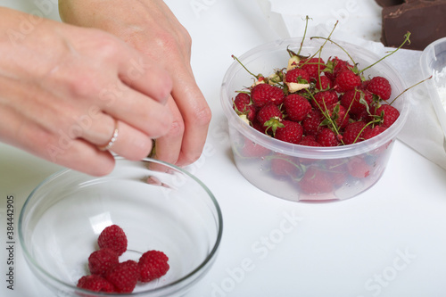 Woman peels raspberries. Levington cake, stages of preparation. photo