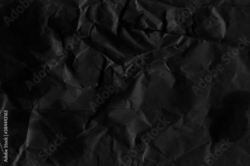 Black vintage and old looking crumpled paper background. Retro cardboard texture. Grunge paper for drawing. Ancient book page. Present wrapping.