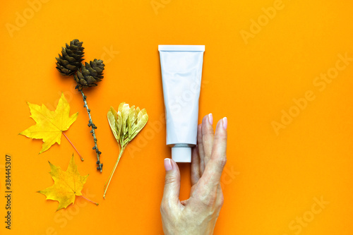 Organic autumn face or body cream on female hand on orange background with copy space. Skin care. skin food