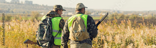 Fotografia, Obraz Duck hunters with shotgun walking through a meadow.