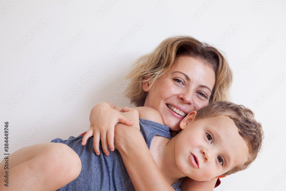 Portrait of happy mother with cute kids boy sitting on a light background. Happy family concept. Portrait of happy mother with cute kids boy sitting on a light background. Happy family concept.