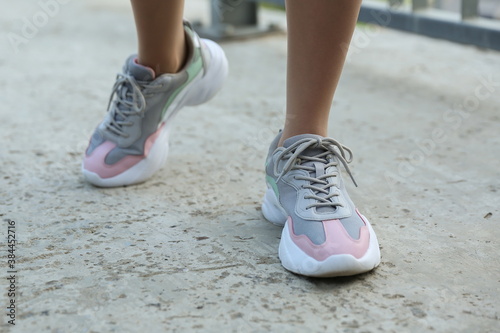 female legs in sports sneakers close-up on the street outdoors