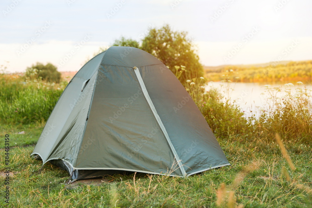 tourist tent is by the river in summer at sunset.