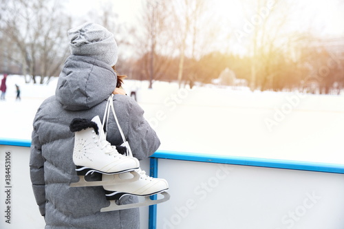 girl holding skates near the rink and looking forward