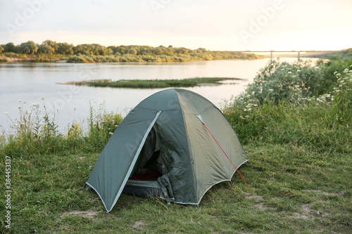 tourist tent is by the river in summer at sunset. © Петр Смагин