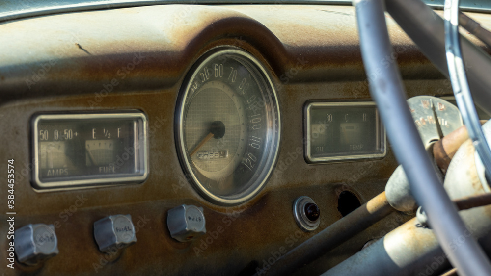 An aged and dusty dashboard of a classic car from the 1950's.