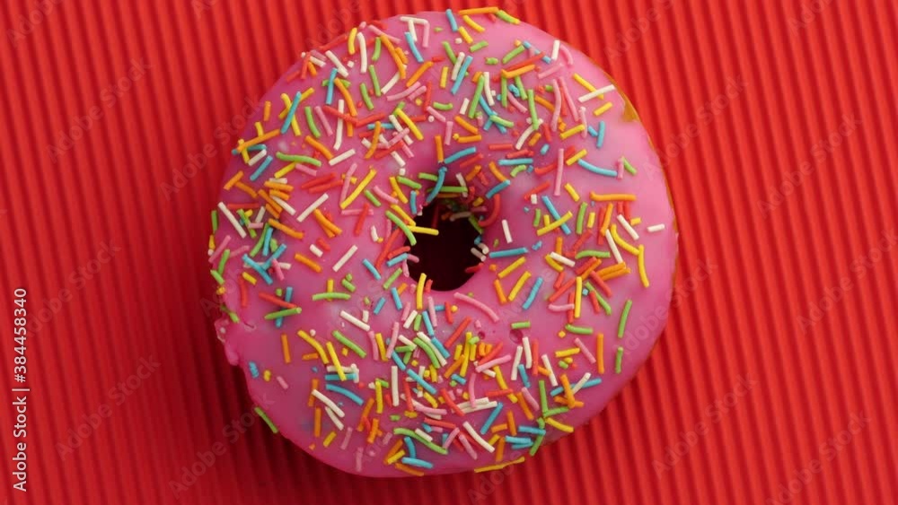 Bright and colorful sprinkled donut close-up shot spinning on a color disposable paper plate.
Bright and colorful sprinkled donut close-up shot spinning on a color disposable paper plate.