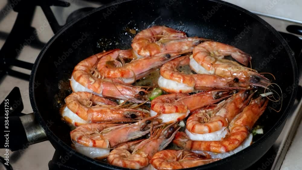 Black Tiger Shrimps Roasted with herbs. Grilled fresh shrimps on gas stove being fried in pan with butter or oil. Frying raw prawns. Concept of cooking shrimps with spices. Close-up closeup macro 4K Black Tiger Shrimps Roasted with herbs. Grilled fresh shrimps on gas stove being fried in pan with butter or oil. Frying raw prawns. Concept of cooking shrimps with spices. Close-up closeup macro 4K