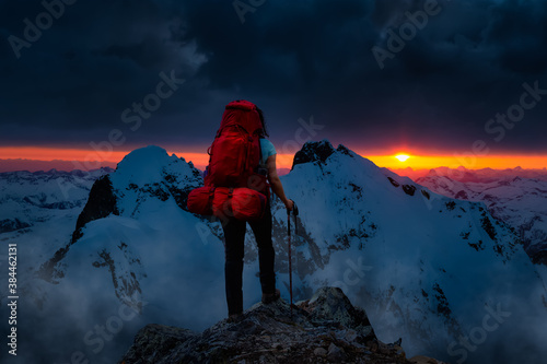 Girl Backpacker on top of a Mountain Peak. Dreamscape Artistic Render Composite. Landscape background from British Columbia, Canada. Dark Dramatic Sunset Sky.