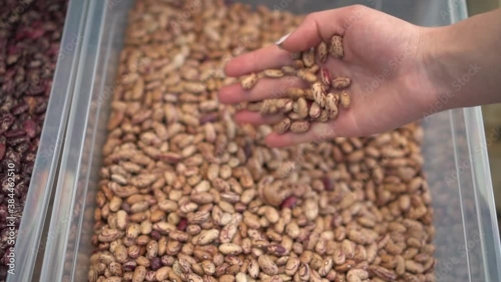 A woman is pouring white beans from her hand into a heap in the market close-up. Slow motion. A woman is pouring white beans from her hand into a heap in the market close-up. Slow motion.