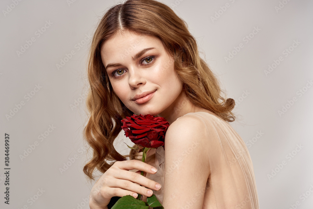 Charming woman with a red rose in her hands on a light background portrait close-up cropped view Charming woman with a red rose in her hands on a light background portrait close-up cropped view