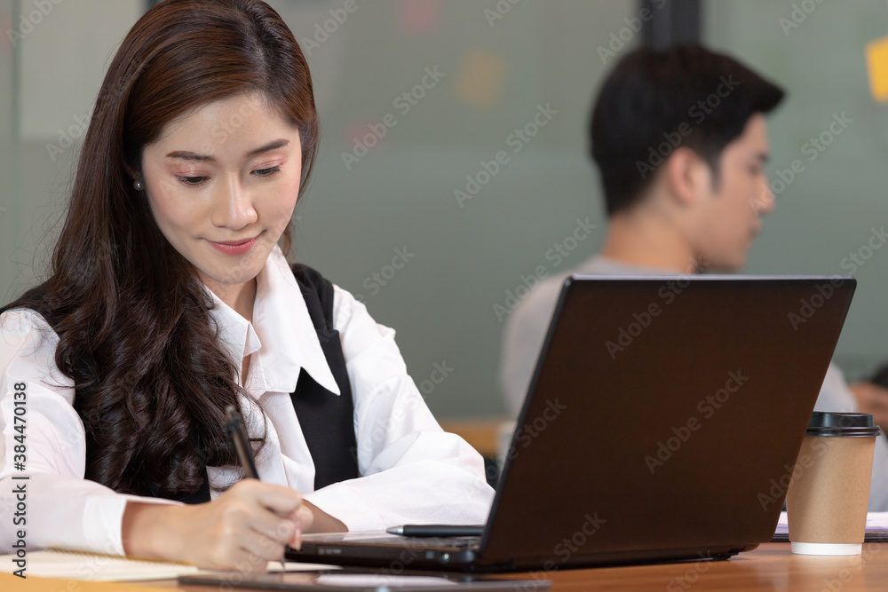 Asian business woman use labtop and note job on paper in office. Asian business woman use labtop and note job on paper in office.