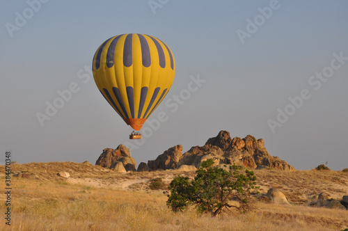 A yellow balloon flies close to the ground over Cappadocia, Turkey