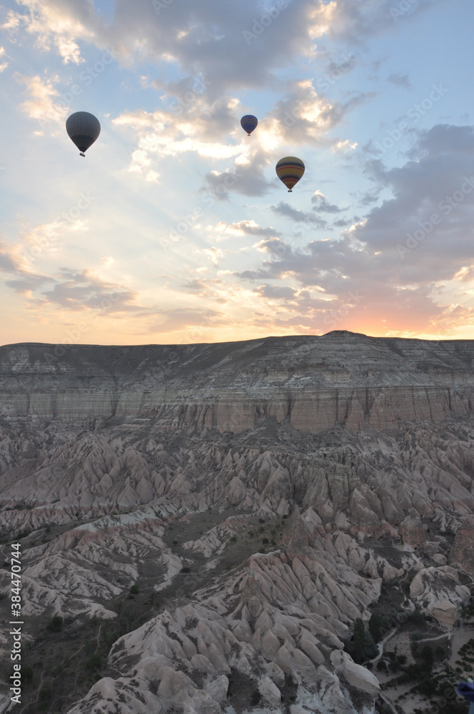 Hot air balloons soar over the mountains and surreal landscape of Cappadocia, Turkey at sunrise Hot air balloons soar over the mountains and surreal landscape of Cappadocia, Turkey at sunrise