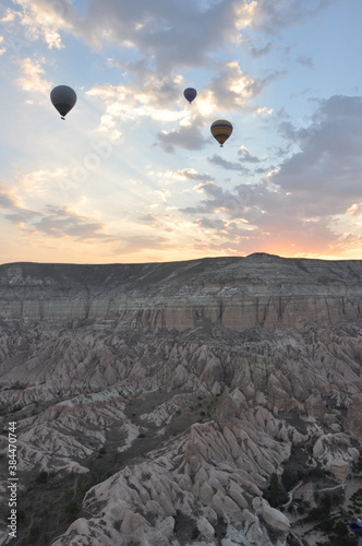Hot air balloons soar over the mountains and surreal landscape of Cappadocia, Turkey at sunrise