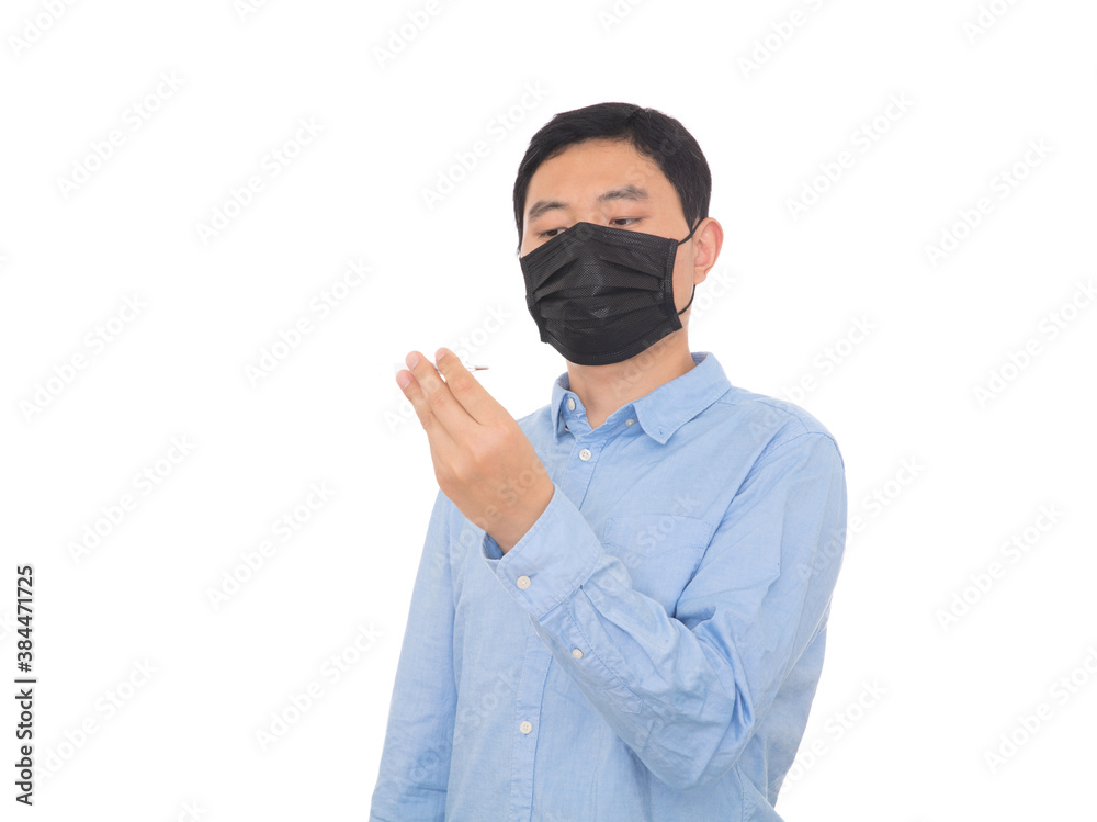 Man wearing mask looking at thermometer in front of white background Man wearing mask looking at thermometer in front of white background