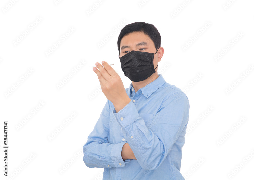 Man wearing mask looking at thermometer in front of white background Man wearing mask looking at thermometer in front of white background