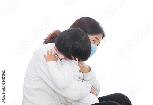 Young mother wearing a mask holding a little daughter wearing a mask