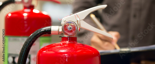 Fire fighter are checking pressure gauge of red fire extinguishers tank in the building concepts of fire prevention and safety of fire services training.