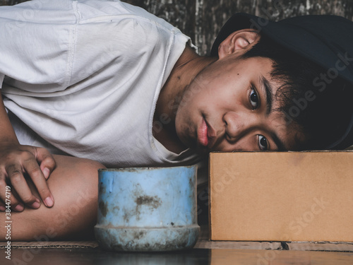 Unfortunate stray kid lay down on dirty floor on the bridge and need someone help for food and money. Poverty, hunger people and human rights concept.