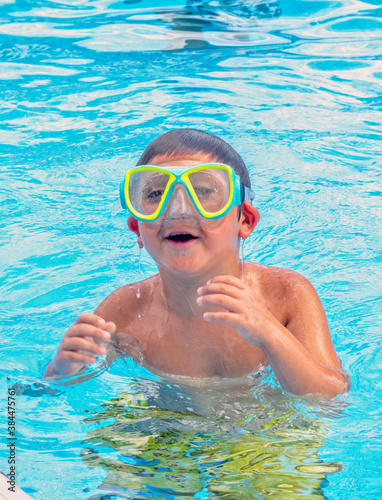 Laughing boy in a swimming pool with swim goggles 