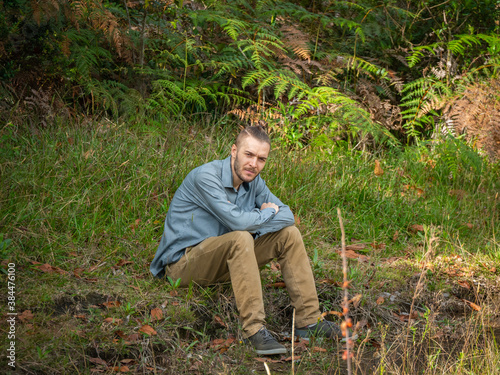 Caucasian Blond Man is Sitting in the Ground in the Middle of the Nature