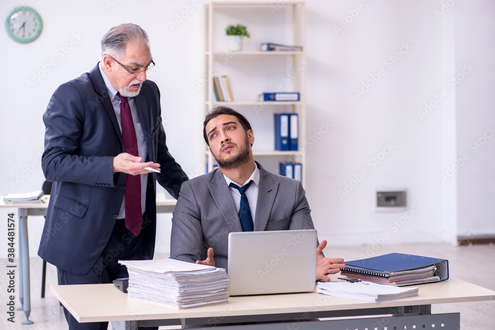 Old boss and his young assistant working in the office Old boss and his young assistant working in the office