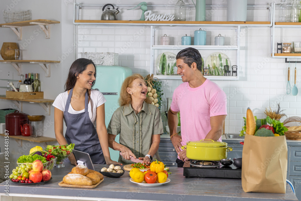 Young couple working with grand mom to take online cooking course and prepare meal at home. Happy family is cooking breakfast with healthy food together Young couple working with grand mom to take online cooking course and prepare meal at home. Happy family is cooking breakfast with healthy food together