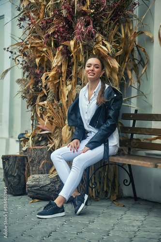 Beautiful young girl in a fashionable leather jacket on a city street