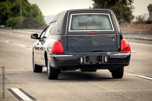 A black hearse driving down a freeway photo