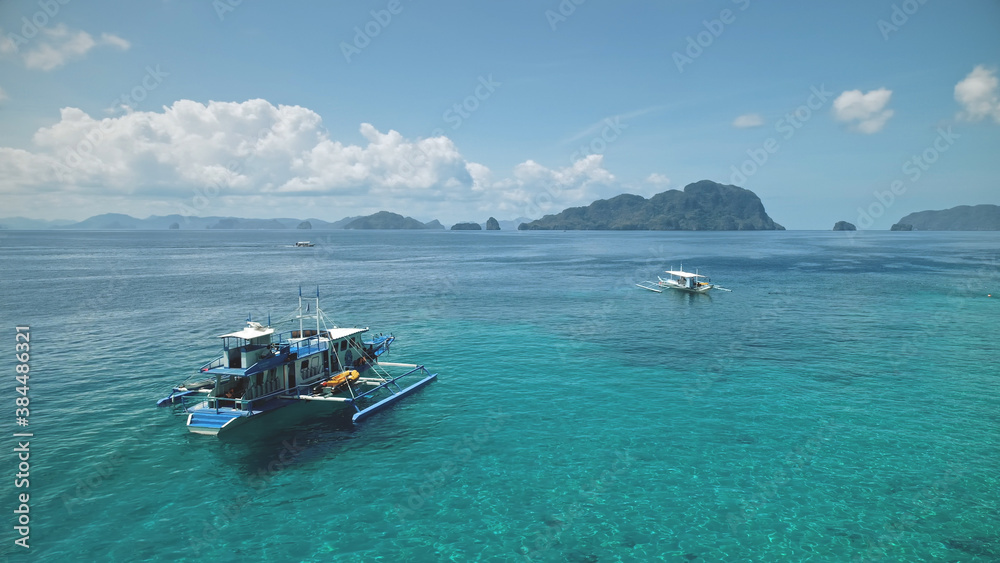 Aerial Philippines ocean bay: boat, ship at turquiose water surface. Local cruise tour for tourist on vessel at sea bay of El Nido Island, Visayas Archipelago, Asia. Tropical seascape in drone shot