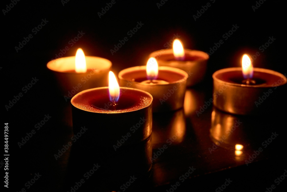 Burning candles on a black background, selective focus, romantic setting, romantic atmosphere, shot with shallow depth of field.