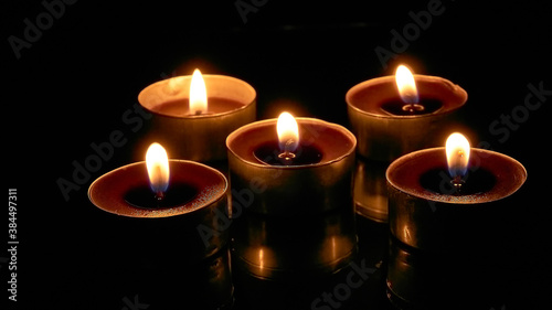 Burning candles on a black background, selective focus, romantic setting, romantic atmosphere, shot with shallow depth of field.