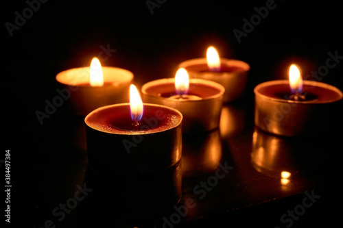 Burning candles on a black background, selective focus, romantic setting, romantic atmosphere, shot with shallow depth of field.