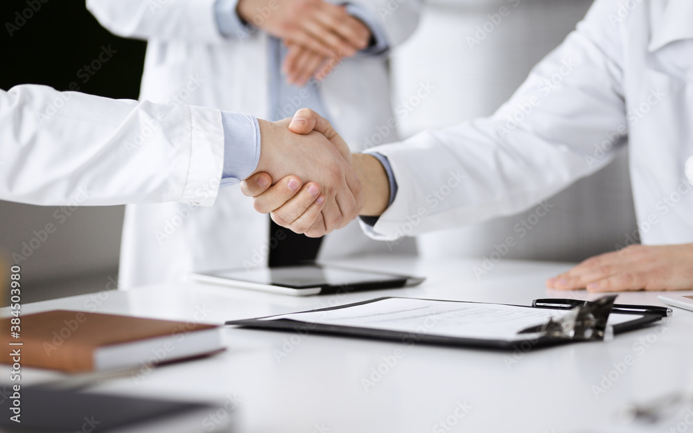 Unknown doctors are shaking their hands as agreement about patient's diagnosis, close-up. Medical help, insurance in health care, medicine concept Unknown doctors are shaking their hands as agreement about patient's diagnosis, close-up. Medical help, insurance in health care, medicine concept