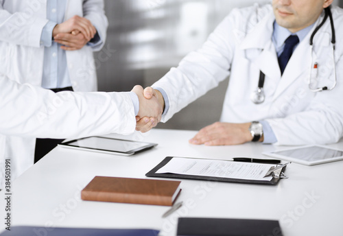Unknown doctors are shaking their hands as agreement about patient s diagnosis  close-up. Medical help  insurance in health care  medicine concept