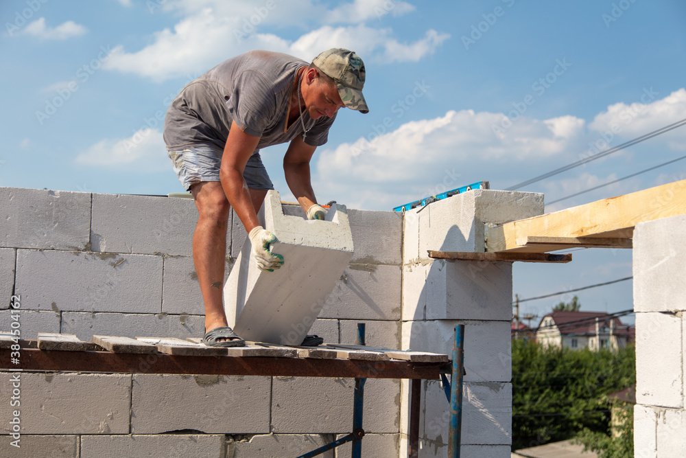 Worker builder lays foam brick in the wall Worker builder lays foam brick in the wall
