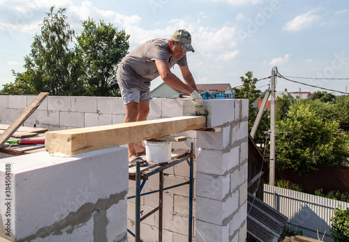 A worker builds the walls of a house from aerated concrete bricks.