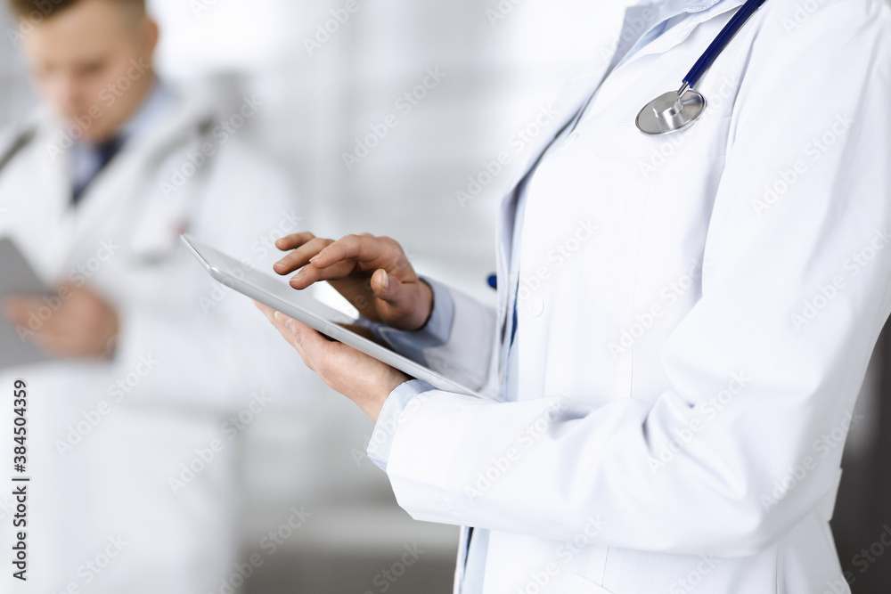 Unknown woman doctor is checking some data at computer tablet, close up. Young doctors at work in a hospital. Medicine and healthcare concept Unknown woman doctor is checking some data at computer tablet, close up. Young doctors at work in a hospital. Medicine and healthcare concept