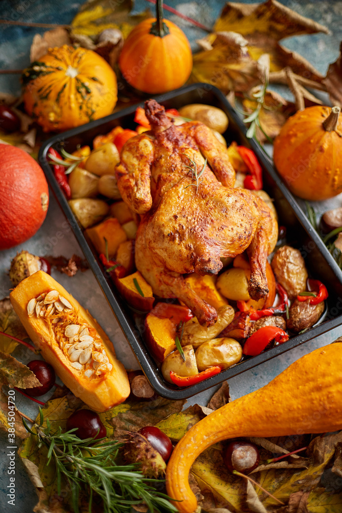 Roasted whole chicken or turkey with pumpkins, pepper and potatoes. With colorful mini pumpkins
