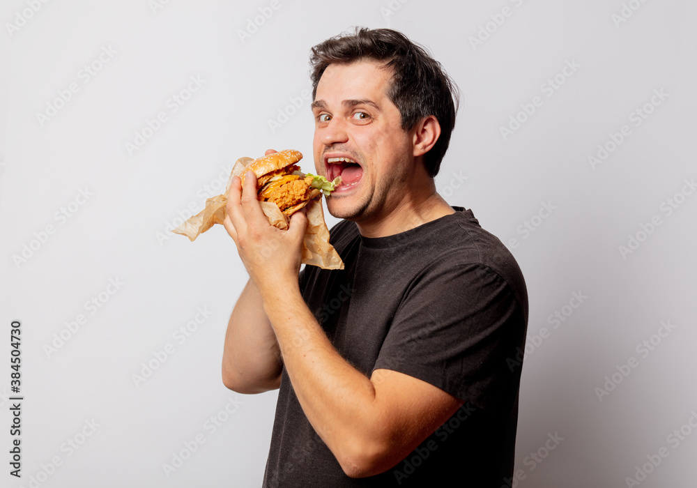 White man in black shirt with burger on white background White man in black shirt with burger on white background